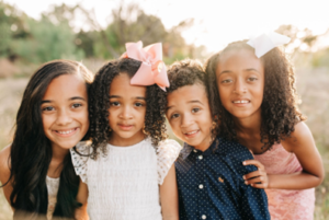 Four children smiling and posing for etiquette class